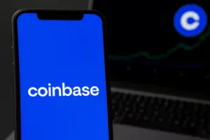 Smartphone showing Coinbase app screen with charts in background, symbolizing Coinbase’s U.S. DEX trading launch.
