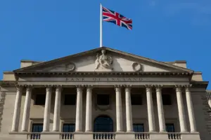 The Bank of England building in London with the UK flag, symbolizing regulation of sterling-denominated stablecoins.