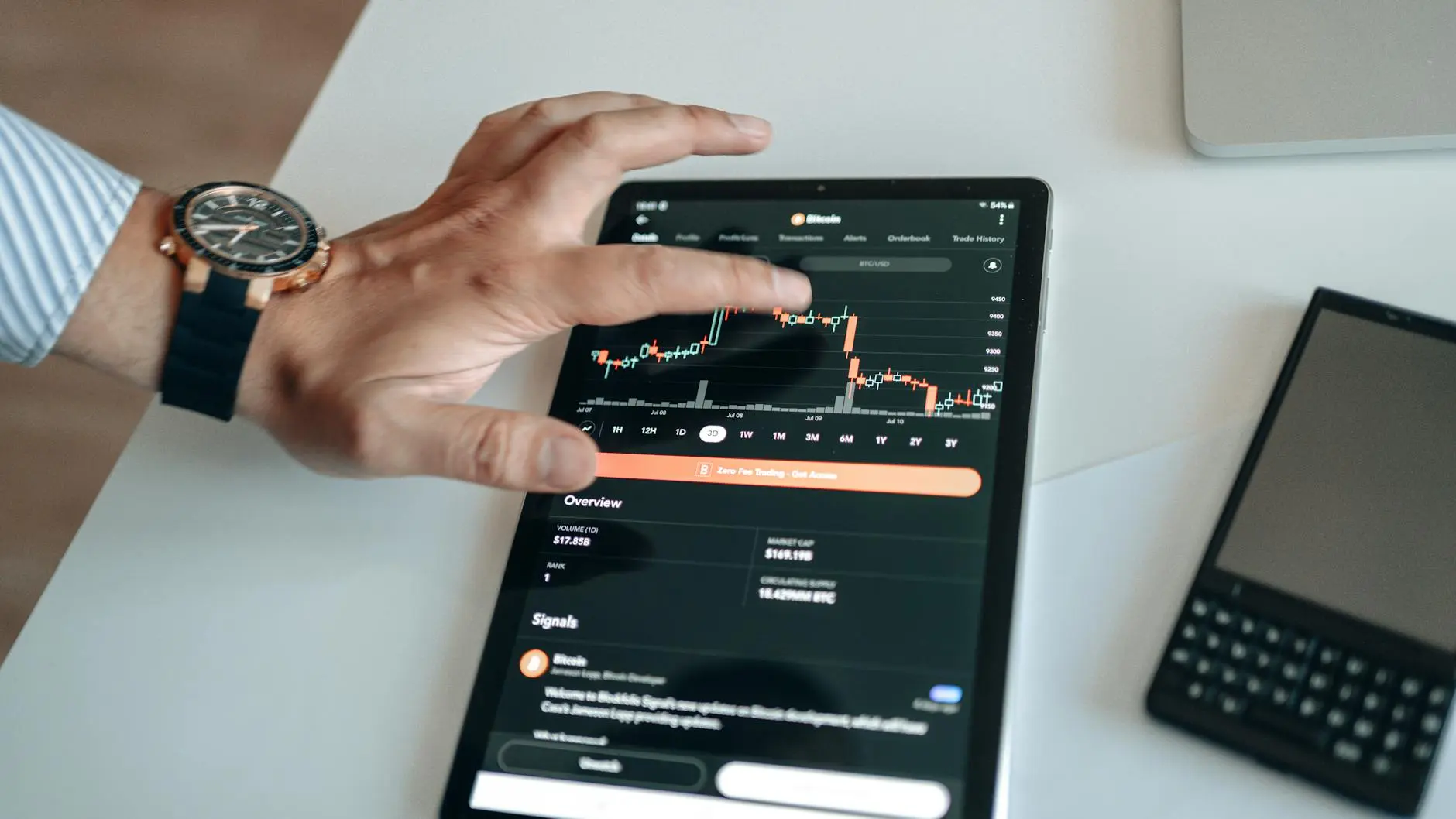 A hand interacting with a crypto trading app showing market charts on a tablet.