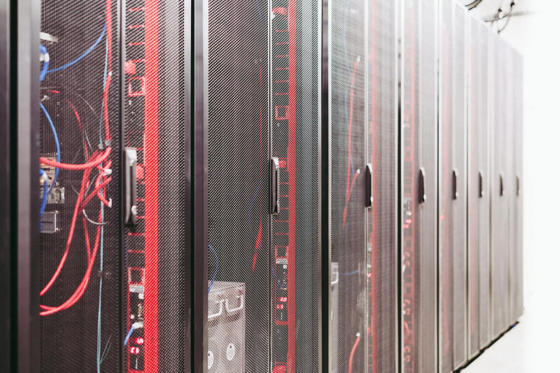 Rows of server racks with visible cables and red lighting in a data center.