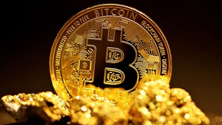 A close-up of a Bitcoin coin with gold nuggets in the foreground.