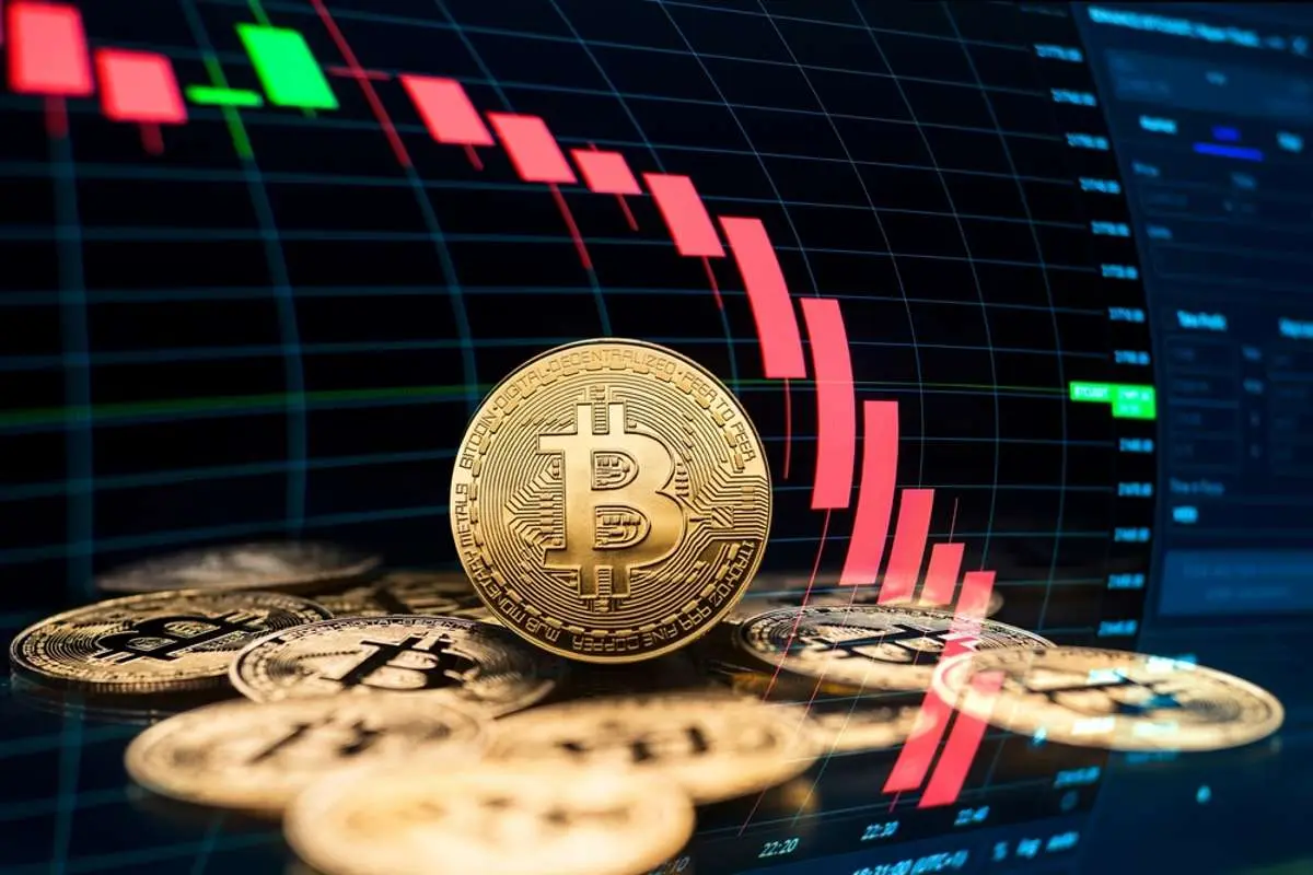 A golden Bitcoin coin in front of a stock market chart showing price fluctuations.