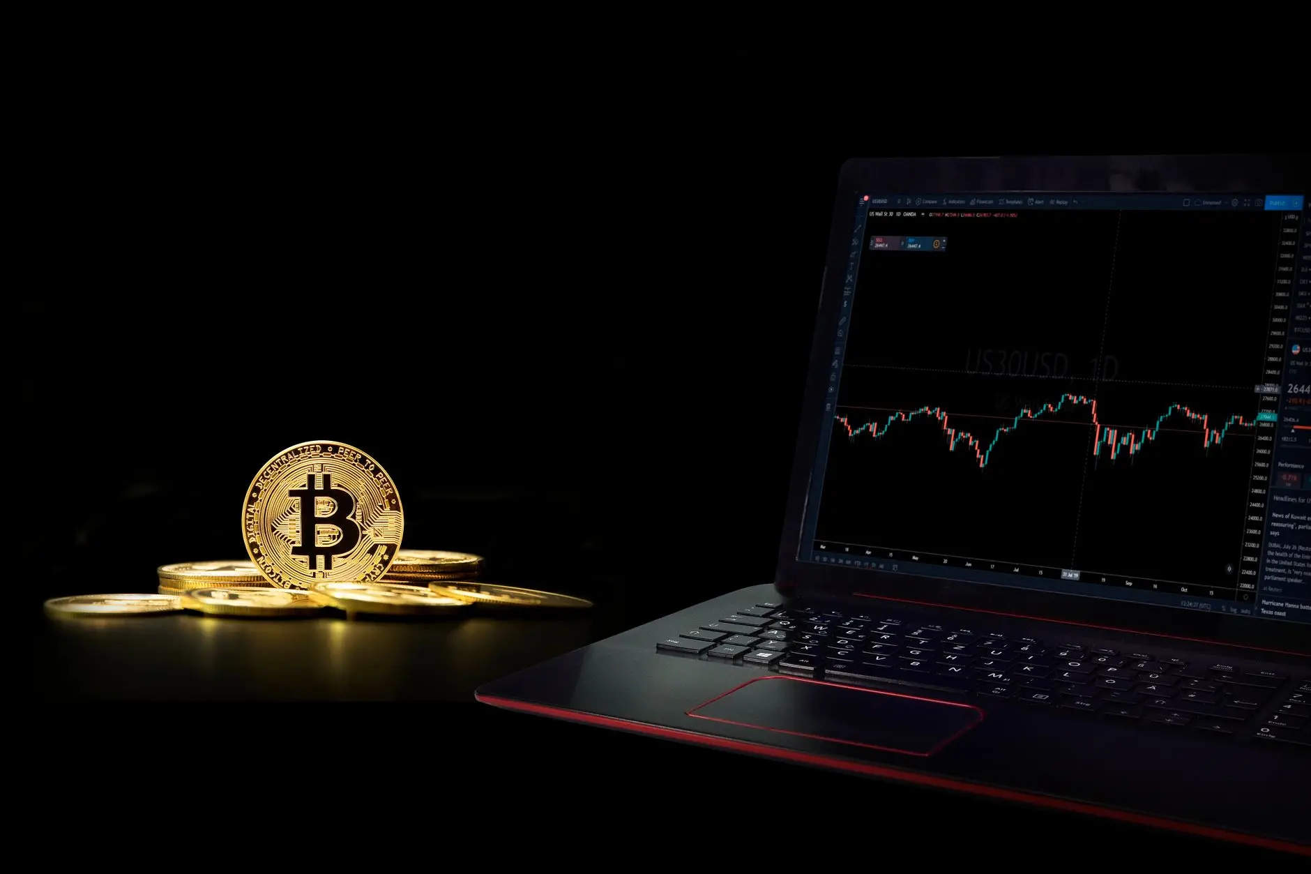 Bitcoin coins with a trading chart displayed on a laptop screen.