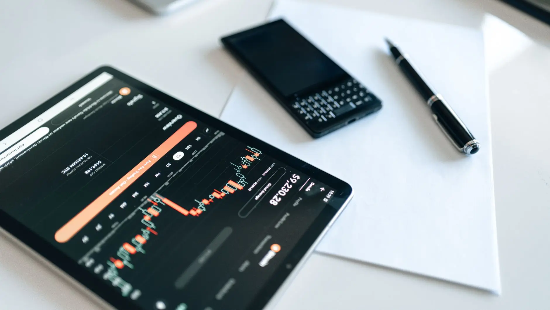 Tablet displaying a cryptocurrency trading chart with a smartphone and pen nearby.