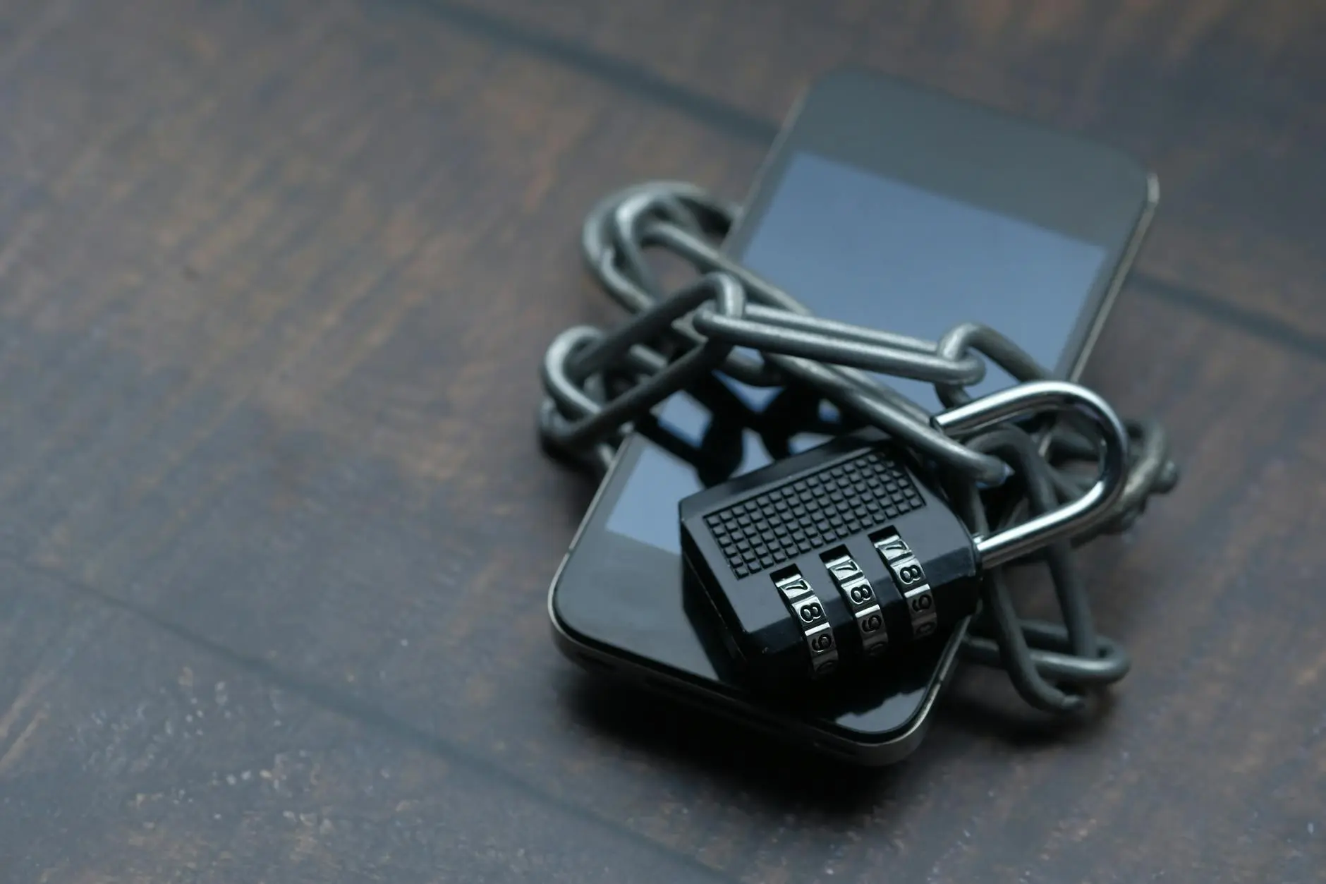 A smartphone wrapped in a chain with a combination padlock.
