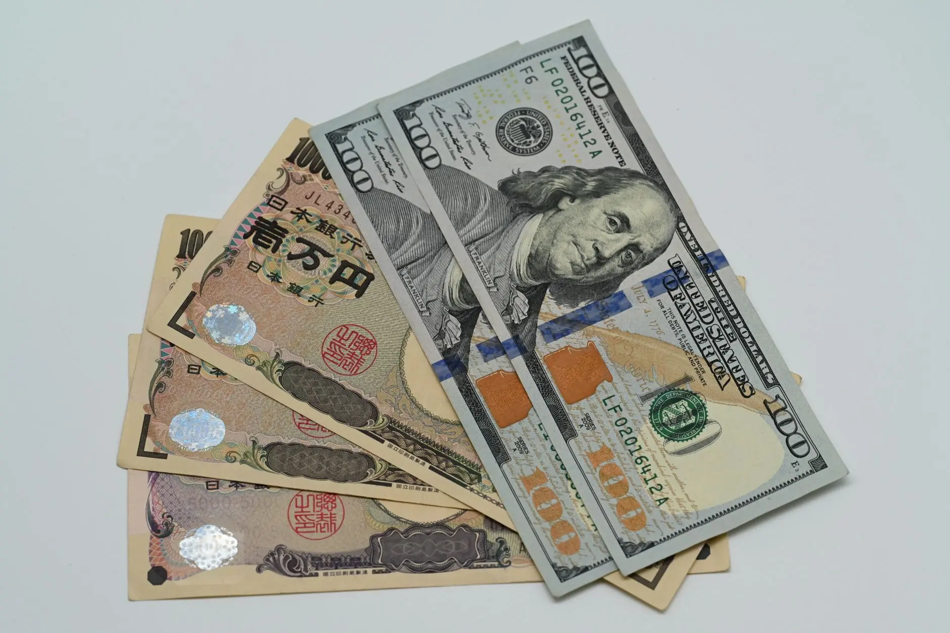 Stack of Japanese yen bills with U.S. dollars on a white background.