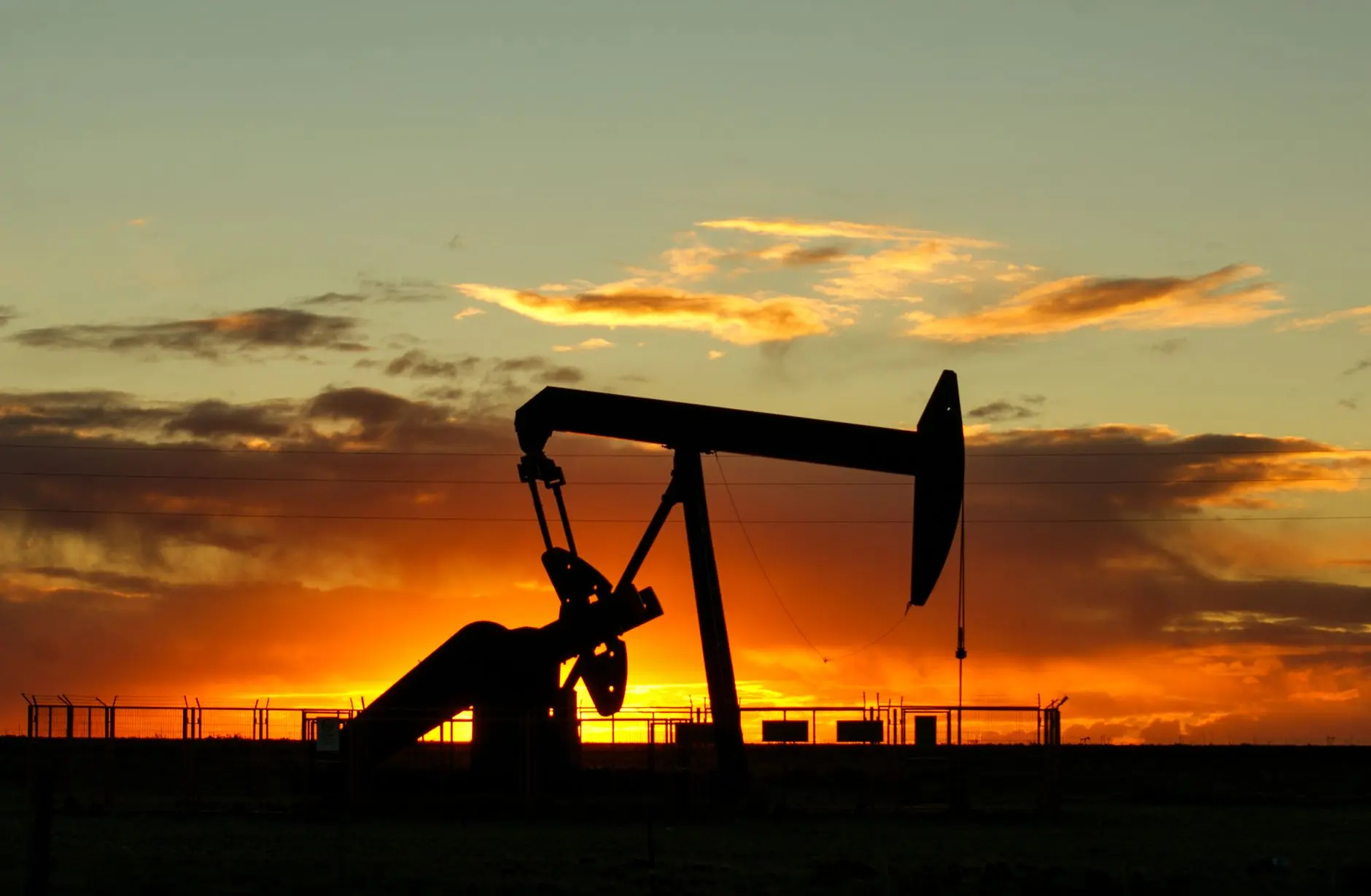 Silhouette of an oil pumpjack against a vibrant sunset.