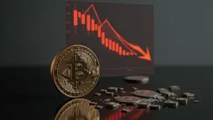 Bitcoin coin and semiconductor chips on dark surface with declining chart visualization in background