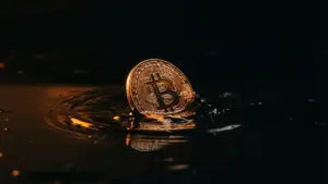 Bitcoin coin emerging from dark water creating ripples symbolizing dormant cryptocurrency movement