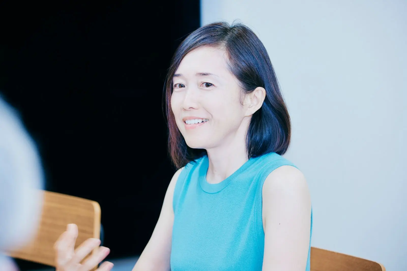Portrait of Aya Miyaguchi wearing a teal sleeveless top, smiling and looking to the side.