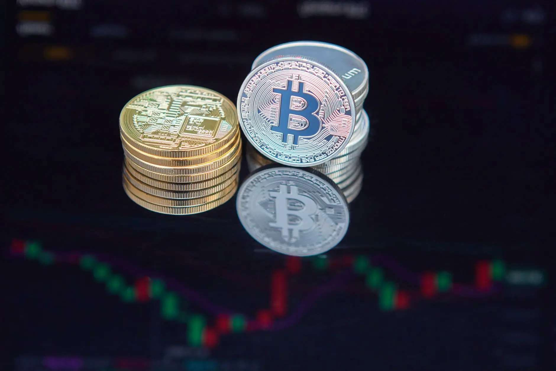 Bitcoin coins displayed in front of a finance chart with color indicators.