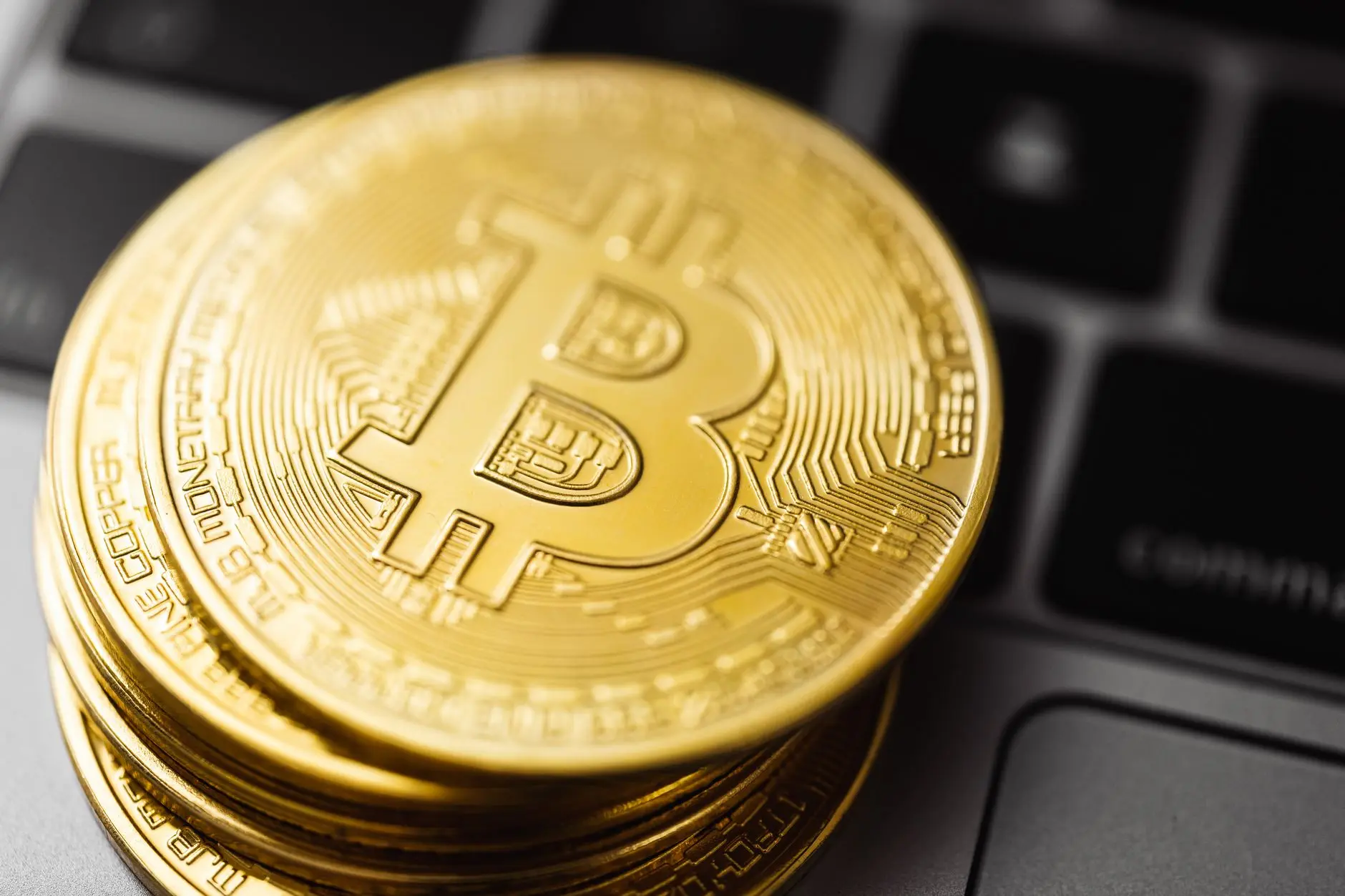 Close-up of stacked gold Bitcoin coins on a laptop keyboard.