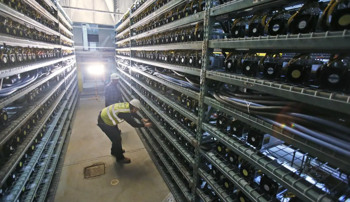 Two workers inspecting Bitcoin mining hardware in a server farm.