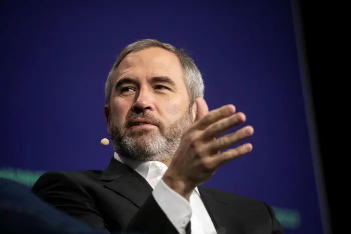 Brad Garlinghouse speaking at a conference, gesturing with his right hand.