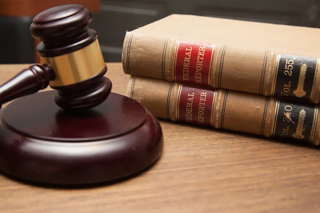 Wooden courtroom gavel beside stacked legal books labeled Federal Reporter.