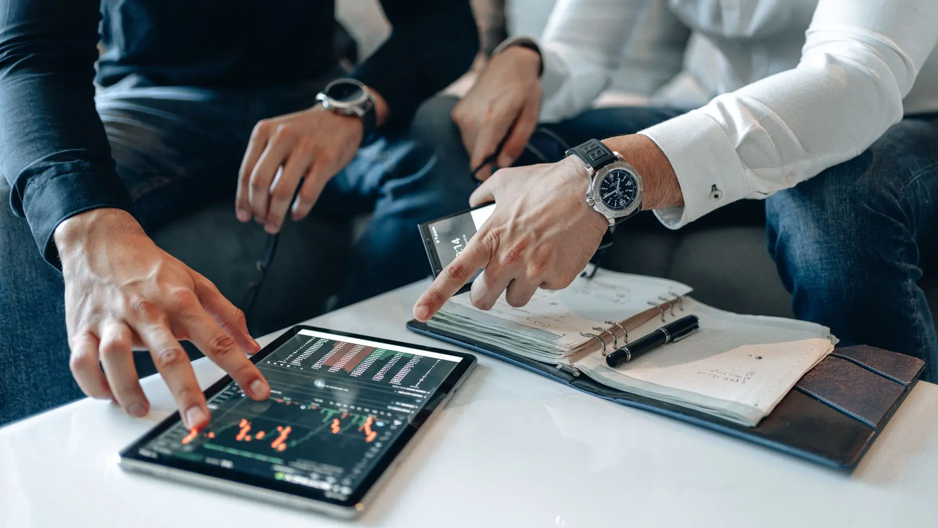 Two individuals analyzing a derivatives data chart on a tablet.