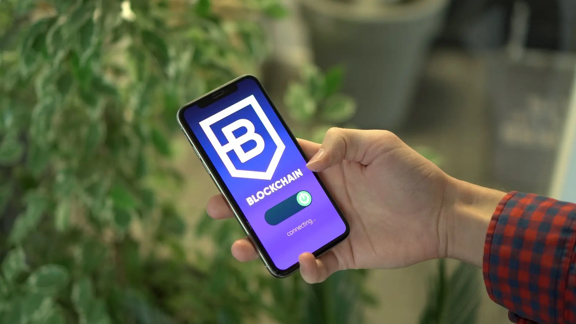 A hand holding a smartphone displaying a blockchain app interface.