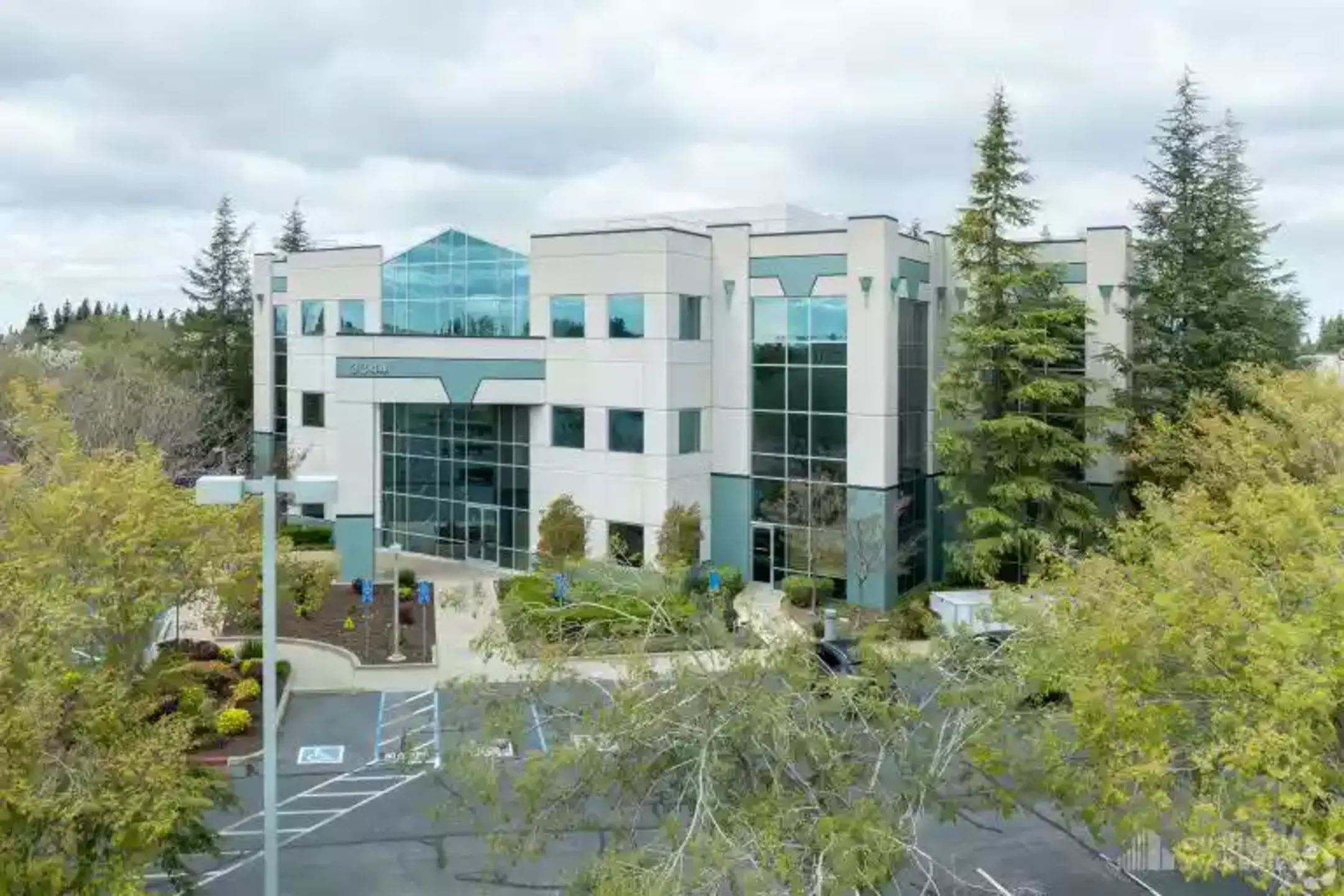 Exterior view of a modern office building surrounded by trees and pavement.
