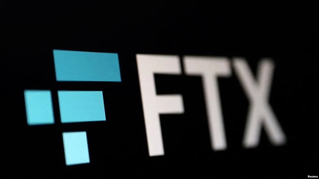 Close-up of the FTX logo with blue and white elements against a dark background.