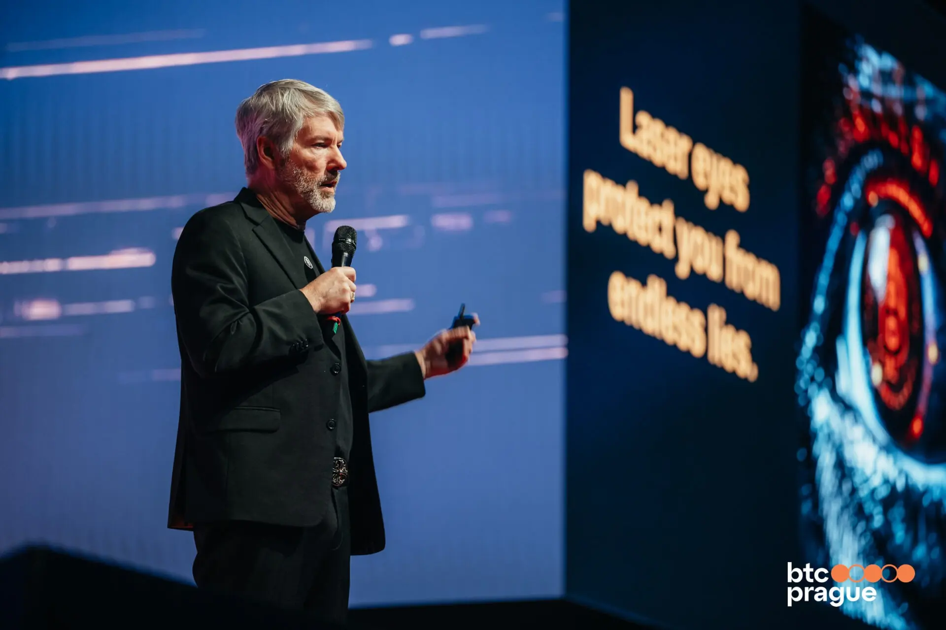 Michael Saylor speaking at a Bitcoin conference with a visual backdrop.