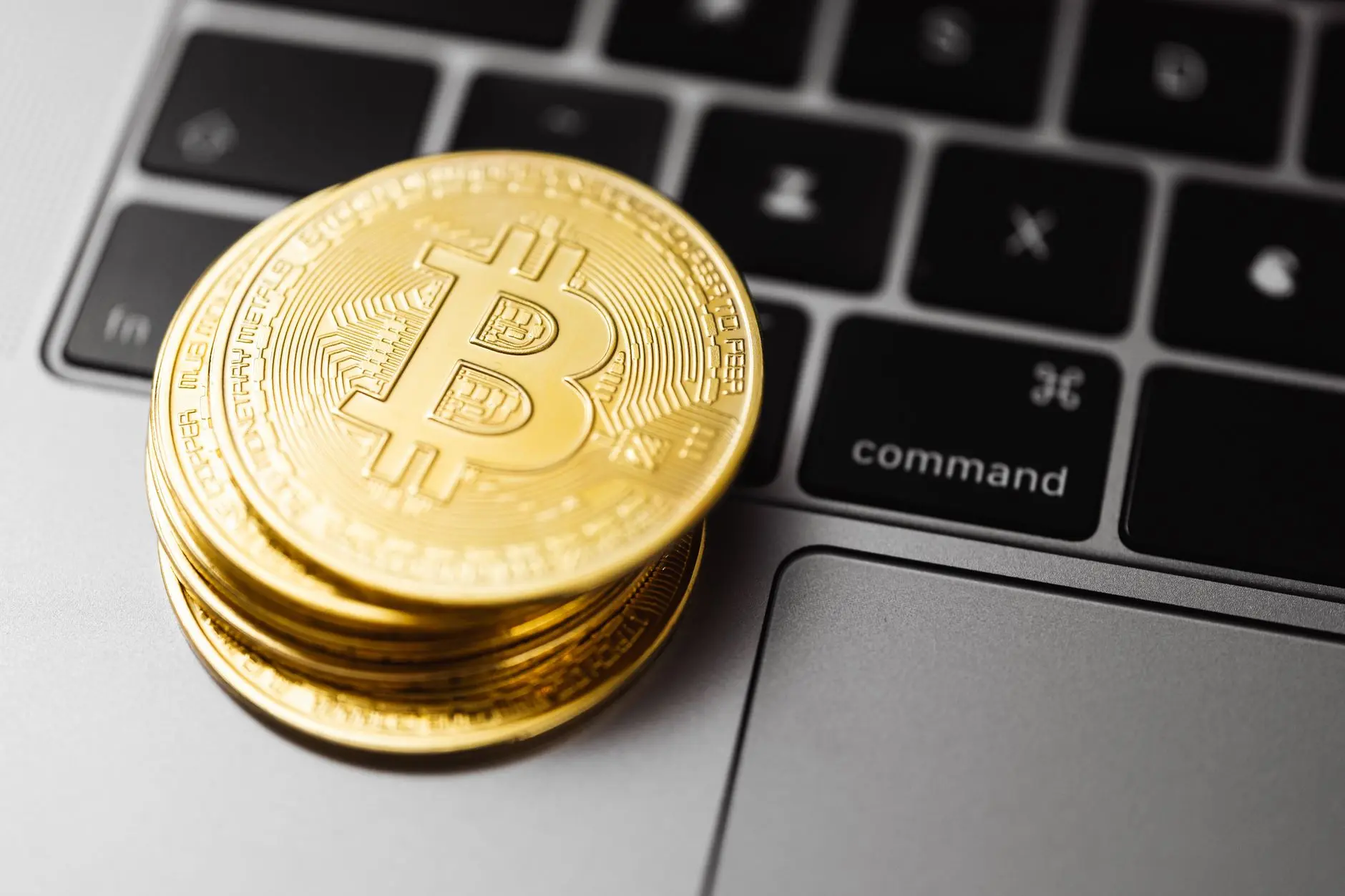 Physical Bitcoin coins stacked on a laptop keyboard.