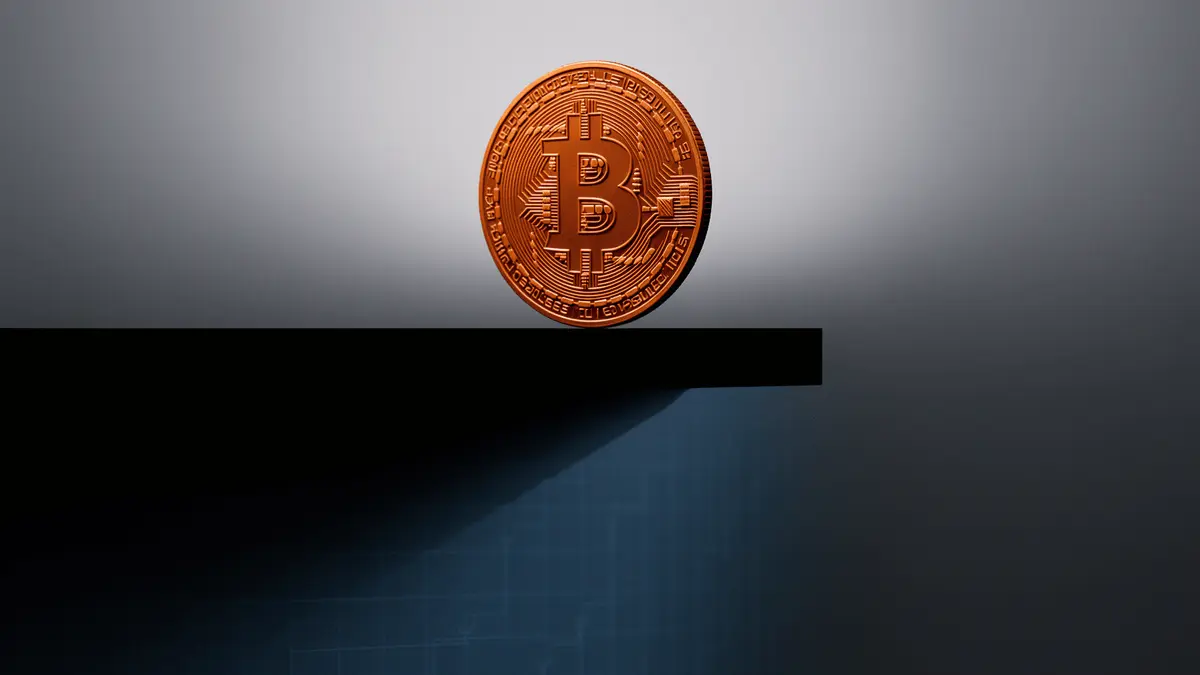 Bitcoin coin on edge of structural precipice representing $52K price floor and market decline