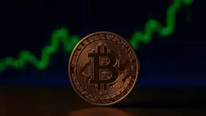 Bitcoin coin on dark surface with rising green chart in background