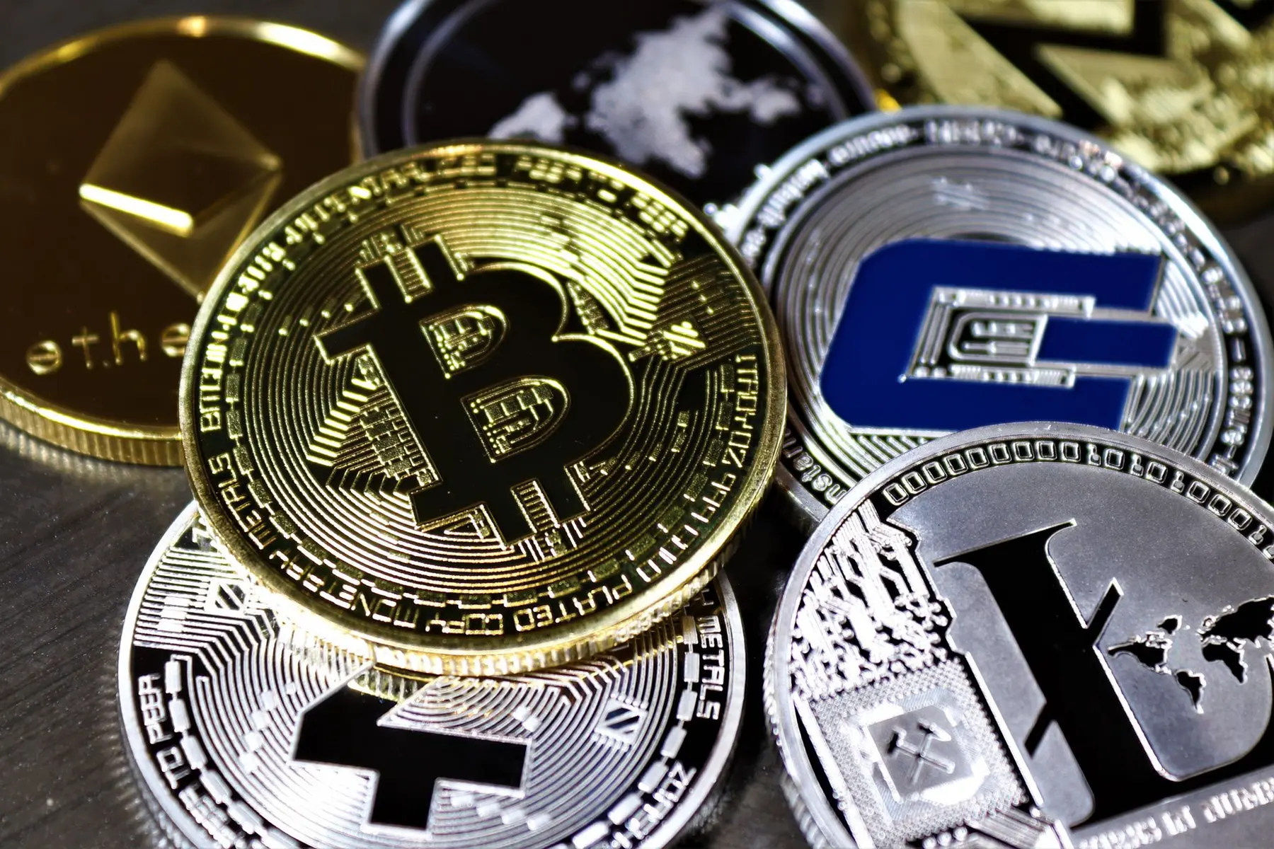 Close-up of various physical cryptocurrency coins including Bitcoin, Ethereum, and Litecoin