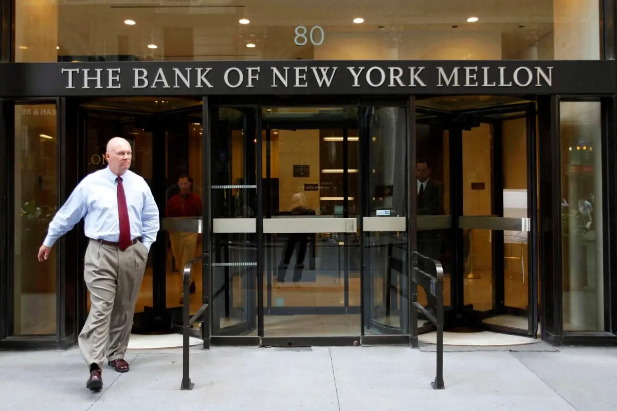 Exterior entrance of The Bank of New York Mellon at 80 Vesey Street with a man walking past.