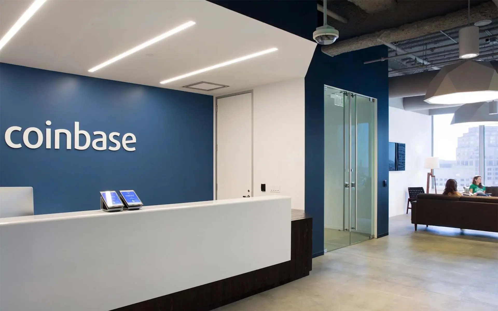 Modern office reception area with a white front desk and the Coinbase logo on a navy blue wall