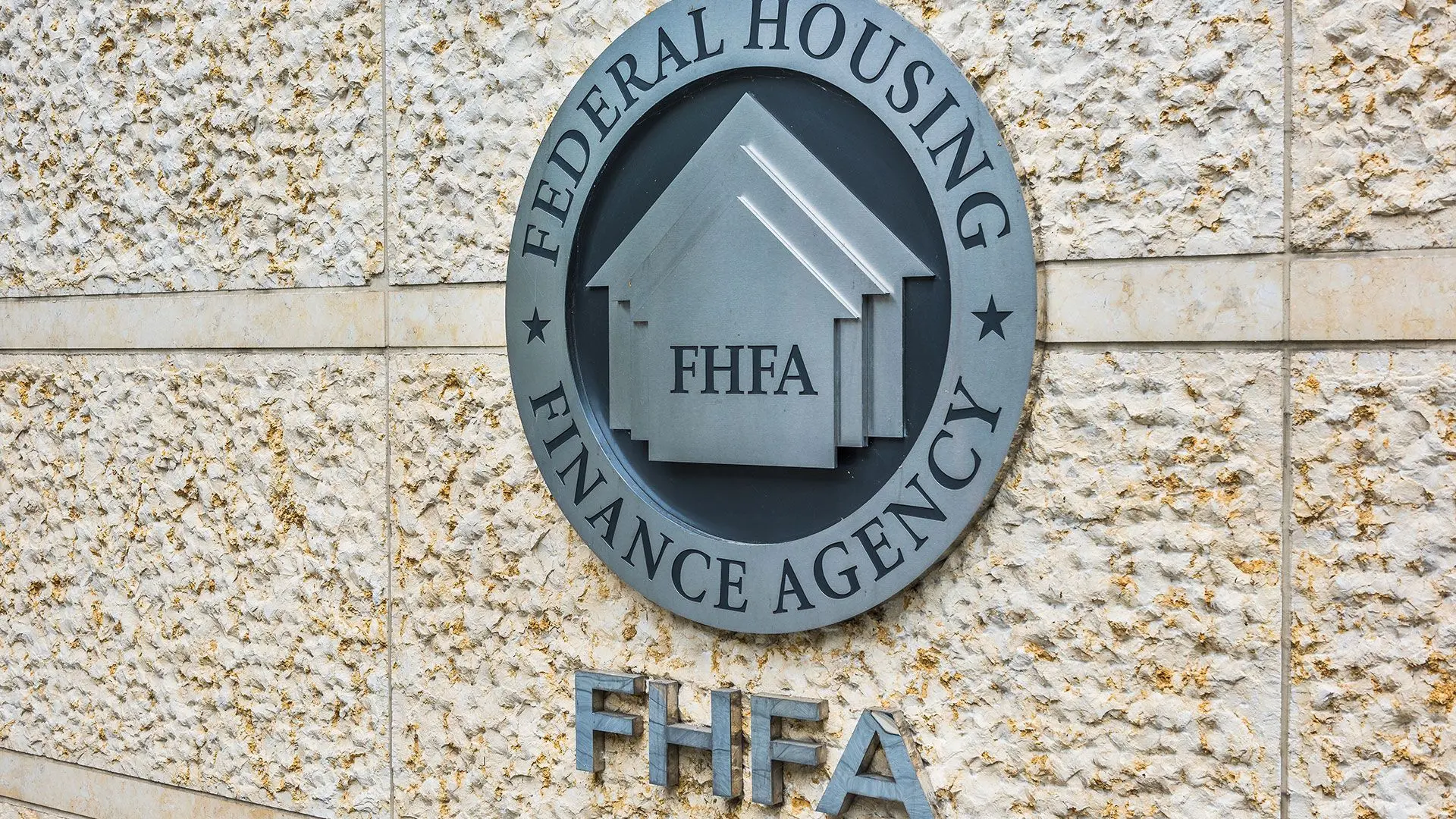 Federal Housing Finance Agency (FHFA) seal and lettering mounted on a textured light-colored stone wall.