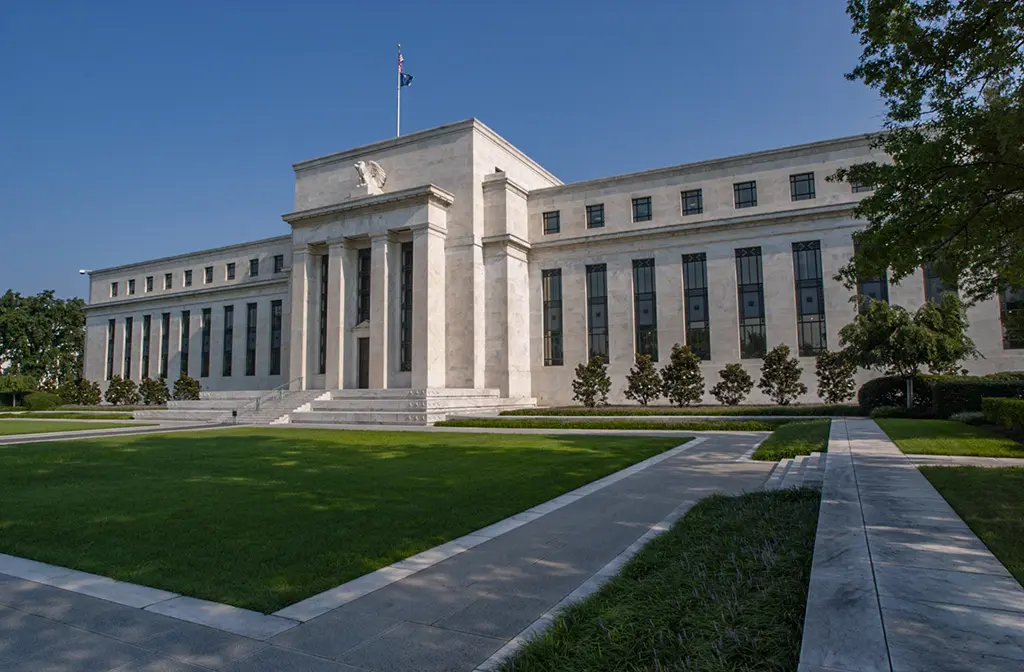 Wide exterior shot of the Marriner S. Eccles Federal Reserve Board Building in Washington DC under a clear blue sky