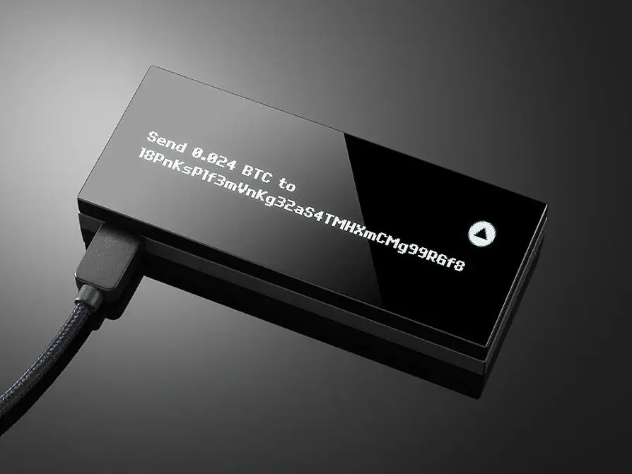 A black KeepKey hardware wallet displaying a Bitcoin transaction address and amount on its screen.
