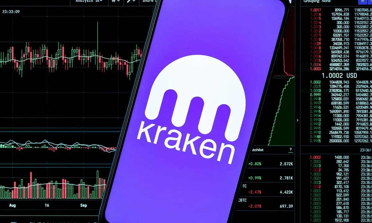 A smartphone displaying the Kraken cryptocurrency exchange logo and name against a background of trading charts.