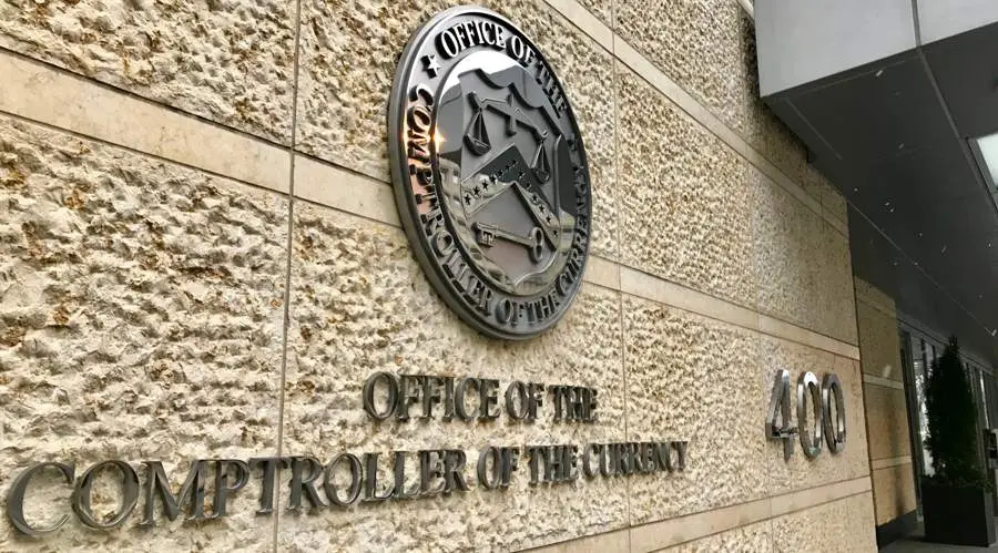 Exterior wall of the Office of the Comptroller of the Currency building featuring its seal and name in metal lettering.