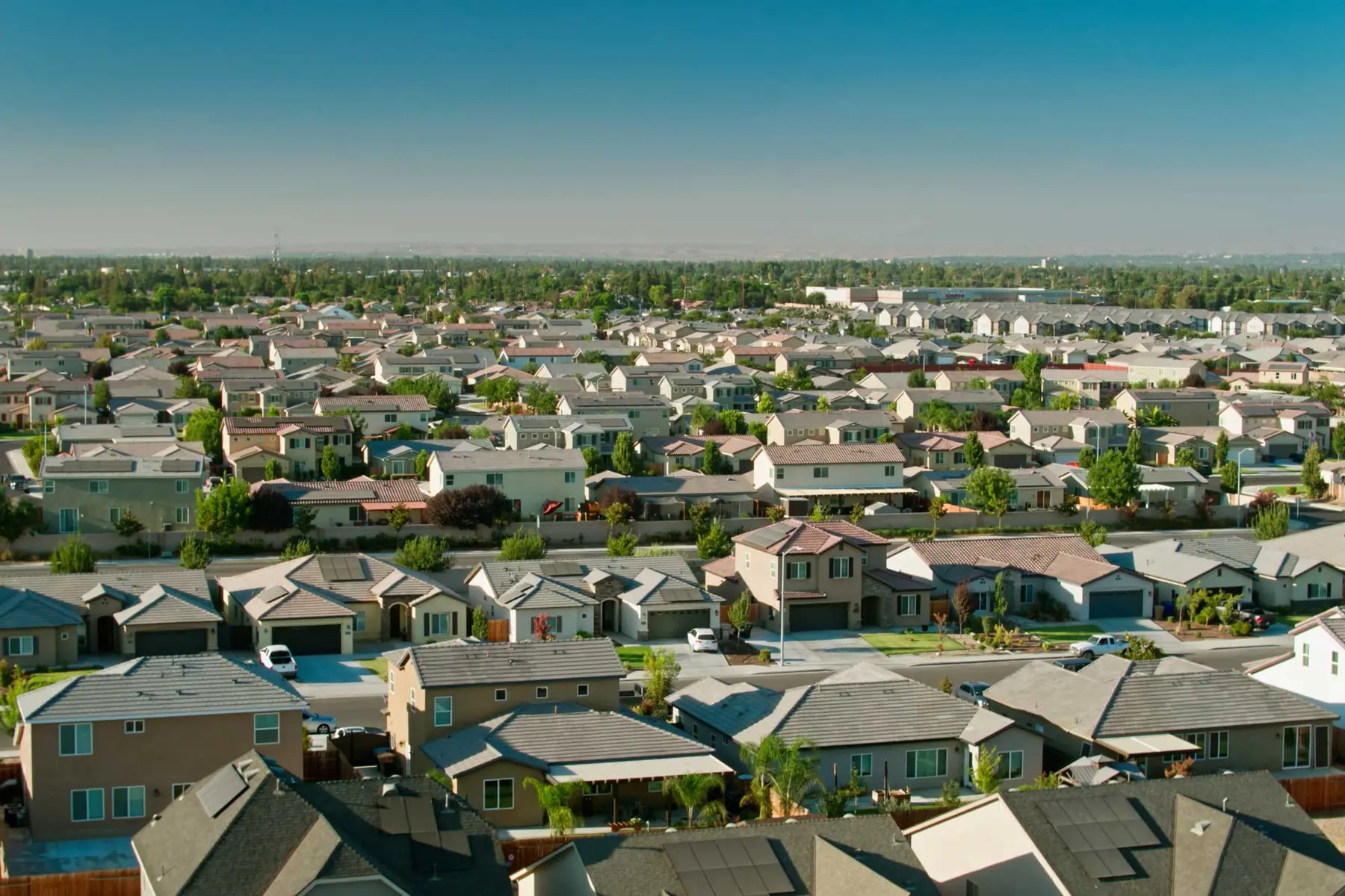 Aerial view of a dense suburban residential neighborhood with modern single-family homes and grey rooftops.