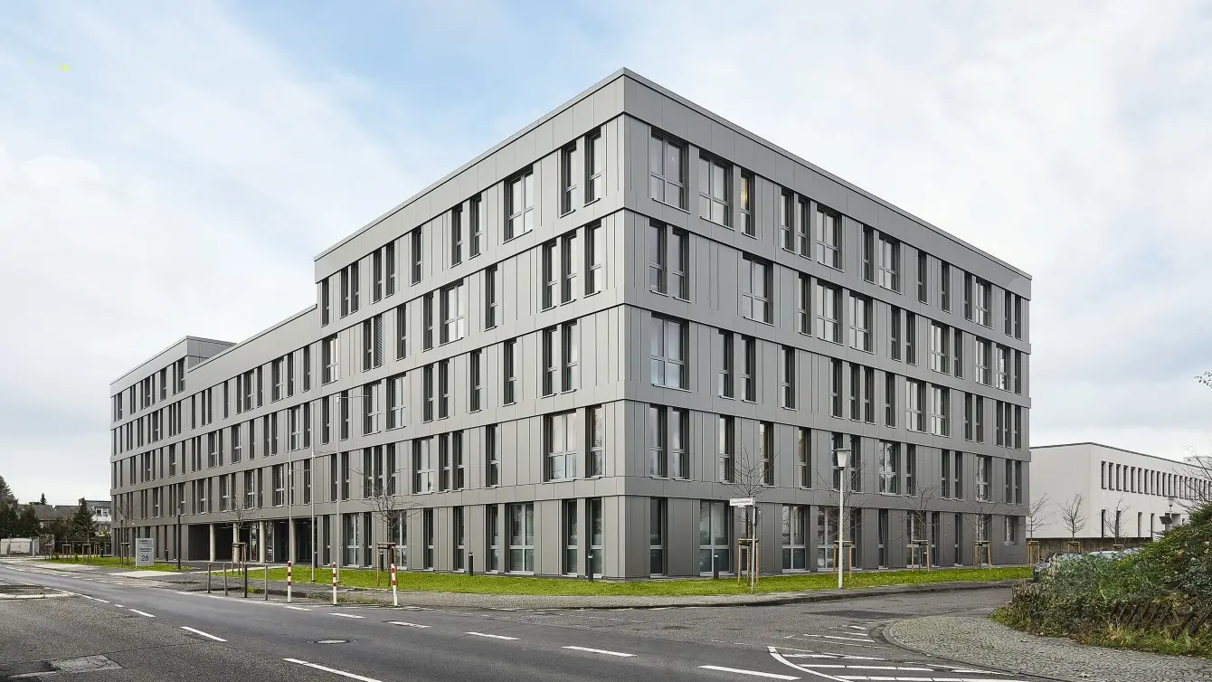 Modern gray office building with a grid of windows and a flat roof under a bright sky in Bonn, Germany