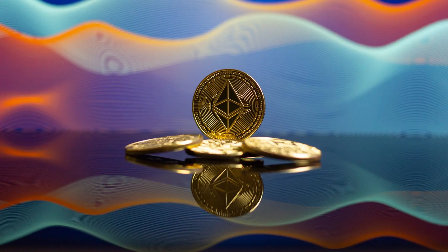 Gold Ethereum cryptocurrency coins on a reflective surface with a wavy blue and orange background