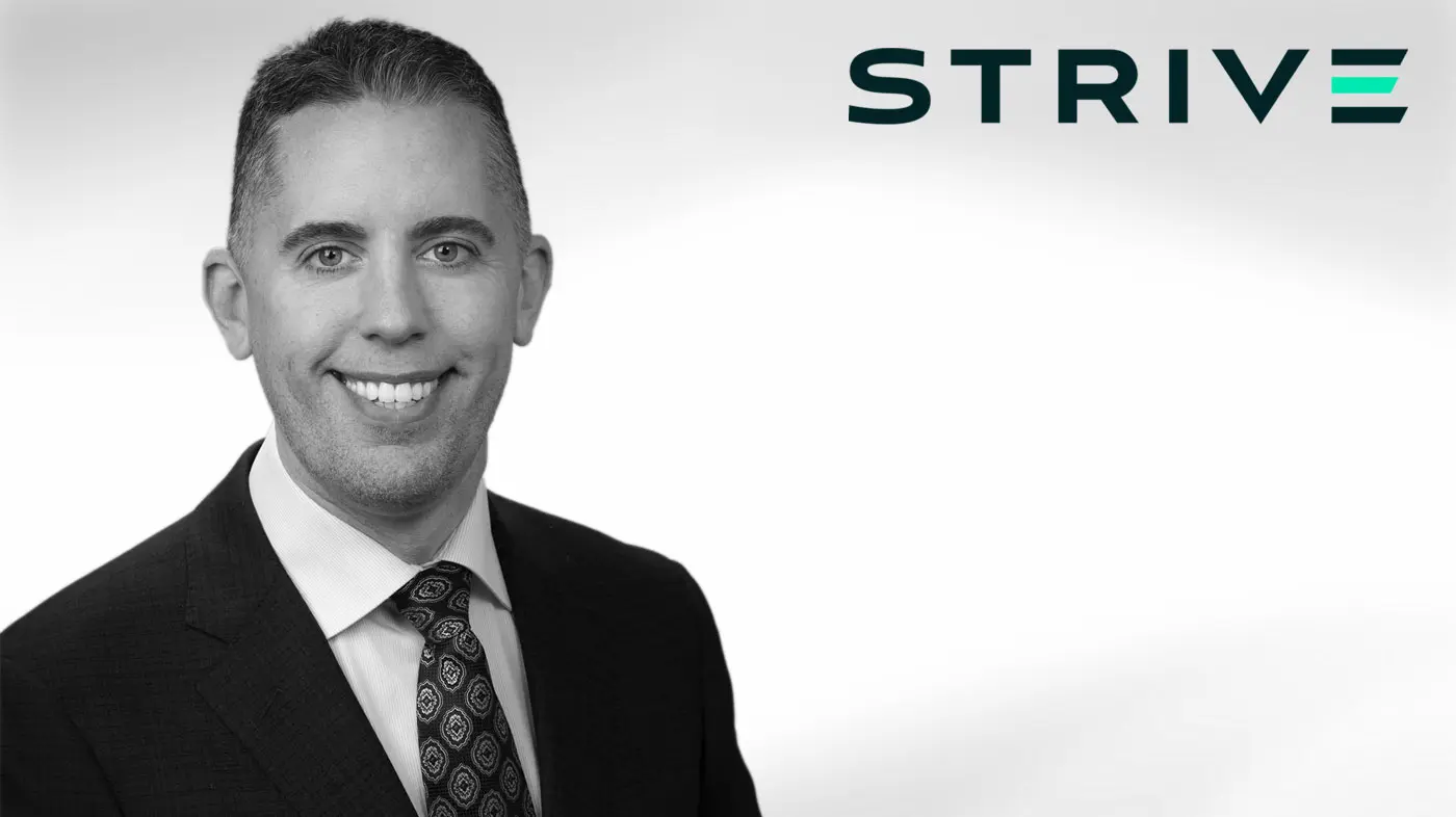 Black and white headshot of Matt Cole, CEO of Strive, wearing a suit and tie with the Strive logo in the background