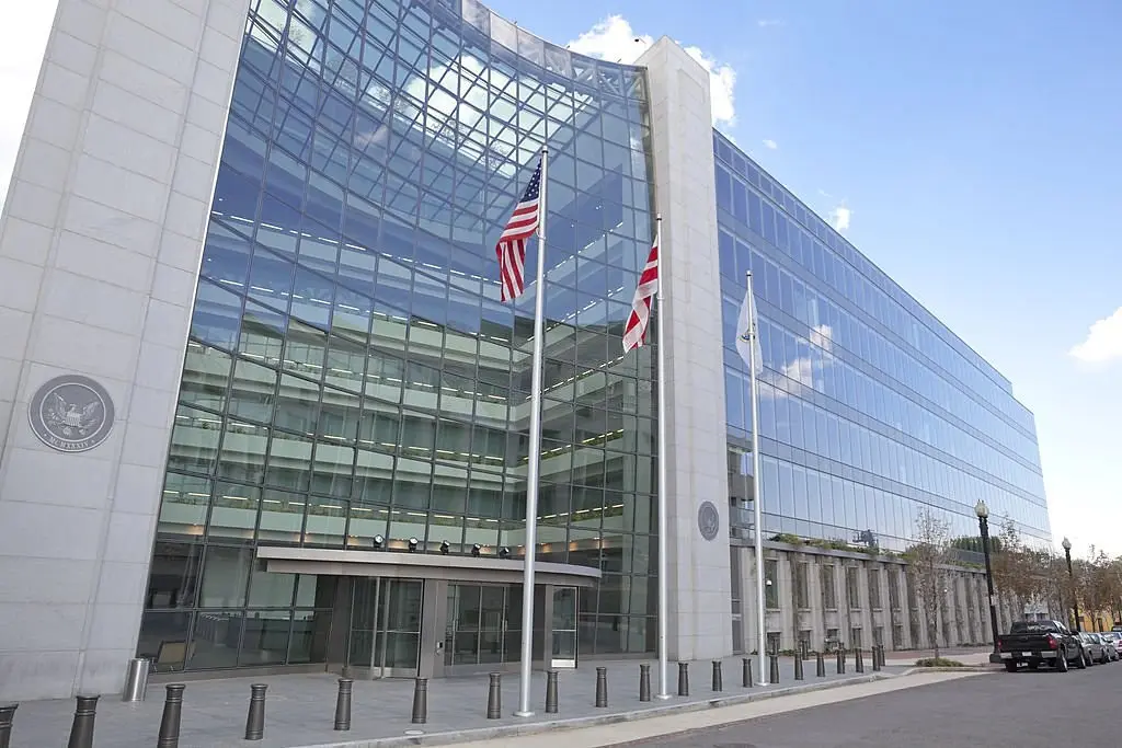 The glass and concrete exterior of the Securities and Exchange Commission building with American flags in front.