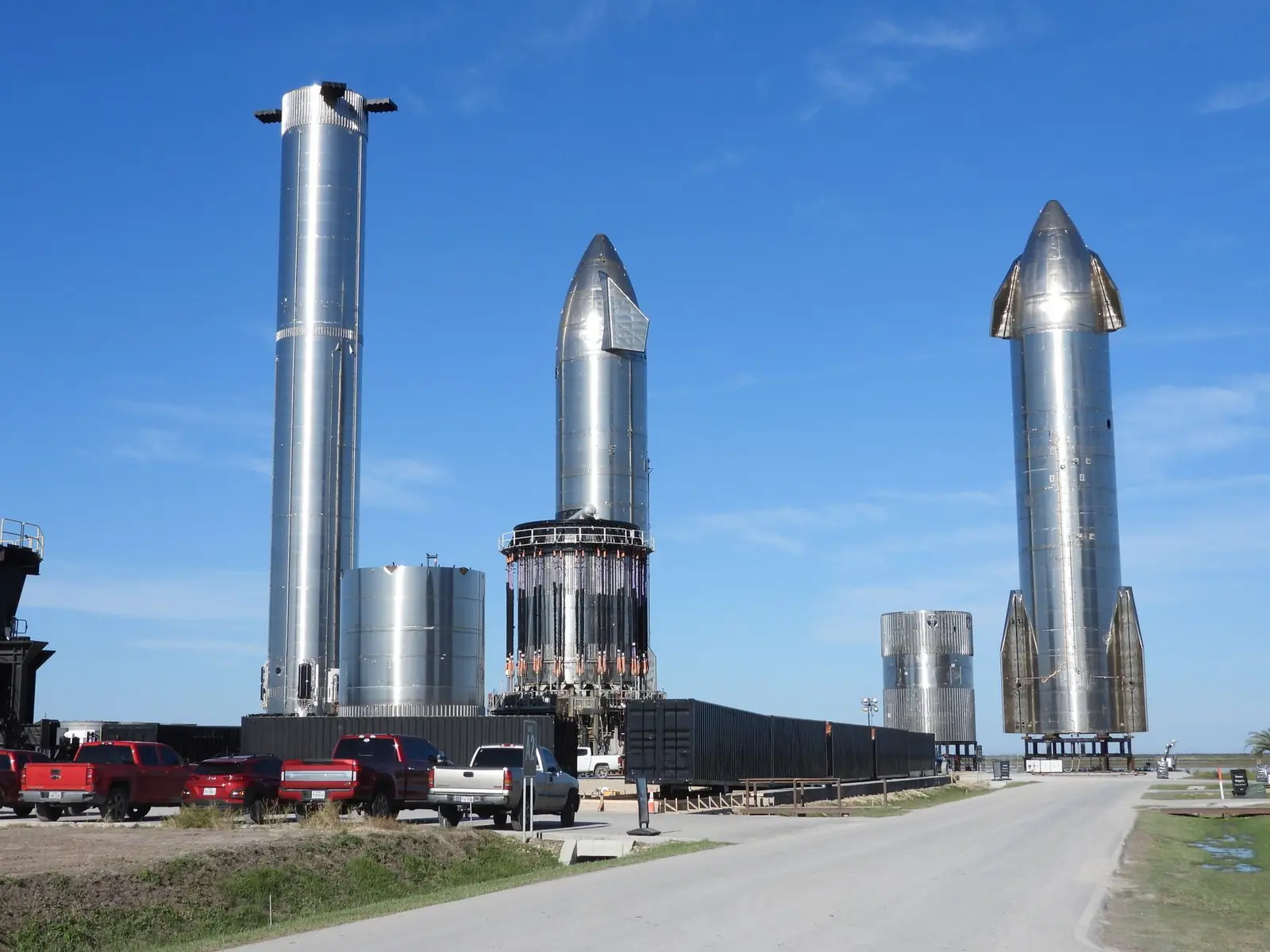 Three stainless steel SpaceX Starship prototypes standing on the launch site in Boca Chica, Texas.